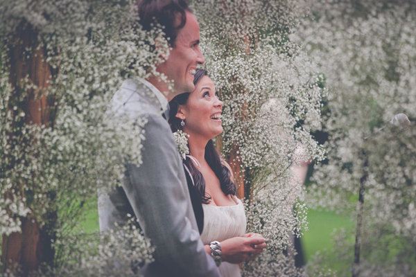 A bride and groom surrounded by an alter of baby's breath